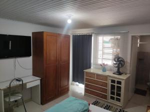 a room with a bedroom with a dresser and a television at HOSTEL INN LAGO in Guarapuava