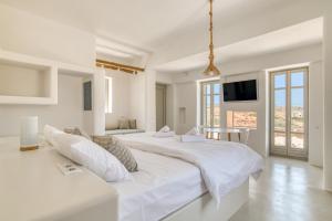 a white bedroom with two beds and a flat screen tv at Lil Paros Luxury suites in Dhragoulás