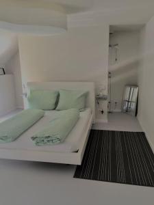 a white bed with two pillows on it in a room at Wohnen direkt am Moselstrand in Bernkastel-Kues