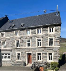 a large stone house with a black roof at Wohnen direkt am Moselstrand in Bernkastel-Kues