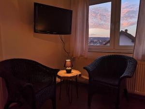 Zimmer mit 2 Stühlen, einem Tisch und einem TV in der Unterkunft Ferienzimmer Schneider in Herbstein