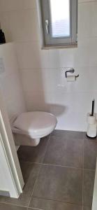 uma casa de banho branca com um WC e uma janela em WH65 gezellig vakantiehuis 4pers. em Koksijde