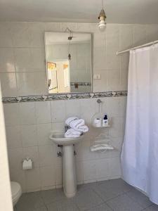 La salle de bains est pourvue d'un lavabo, d'un miroir et de toilettes. dans l'établissement Hostal Villa Italo, à Copiapó