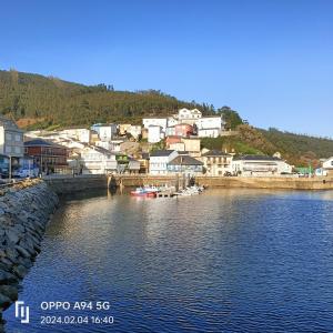 奥维塞多ALQUILER VACACIONAL PLAYA O VICEDO的水体旁的山丘上的城镇