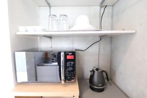una pequeña cocina con una estantería sobre un microondas en Ideal Tennoji - Vacation STAY 15959, en Osaka