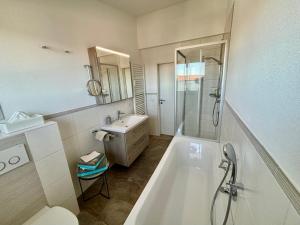 ein weißes Badezimmer mit einer Badewanne und einem Waschbecken in der Unterkunft Ferienwohnung Felderhaldeblick in Isny im Allgäu