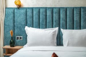 a bed with a blue headboard and white pillows at Maarif elite suites in Casablanca