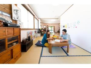 zwei Personen sitzen an einem Tisch in einem Zimmer in der Unterkunft Showa No Toraya - Vacation STAY 61491v in Chikuma