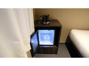 una pequeña televisión en una mesa junto a una cama en Dynasty Hotel Osaka - Vacation STAY 61768v, en Osaka