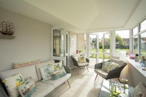 sala de estar con sofá, sillas y ventanas en Harbour cottage sleeps 4 nr Marina Eastbourne en Pevensey
