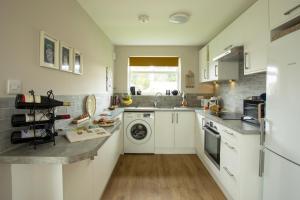 - une cuisine avec des placards blancs et un lave-linge/sèche-linge dans l'établissement Harbour cottage sleeps 4 nr Marina Eastbourne, à Pevensey