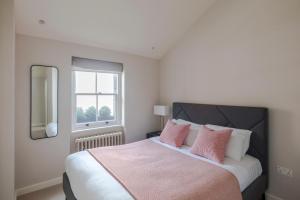 1 dormitorio con 1 cama grande con almohadas rosas en Parkside House - Regent's Park - by Frankie Says, en Londres
