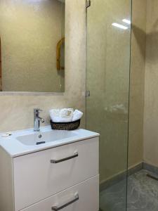 uma casa de banho com um lavatório e uma cabina de duche em vidro. em DAR RITA em Taghazout