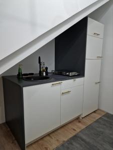 een keuken met witte kasten en een zwart aanrecht bij Ella Green Apartments in Gratkorn