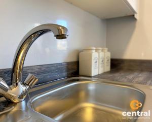 a kitchen sink with a faucet on a counter at Lawson by CENTRAL SERVICED APARTMENTS - Cosy 1 Bedroom - Modern - Close to Transport Links - Quiet Neighbourhood - Fast WiFi - Fully Equipped - Smart TVs in All Rooms - Monthly Stays Welcome - FREE Street Parking - Ideal Relocation to Dundee Accommodation in Dundee