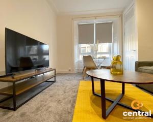 a living room with a large flat screen tv at Lawson by CENTRAL SERVICED APARTMENTS - Cosy 1 Bedroom - Modern - Close to Transport Links - Quiet Neighbourhood - Fast WiFi - Fully Equipped - Smart TVs in All Rooms - Monthly Stays Welcome - FREE Street Parking - Ideal Relocation to Dundee Accommodation in Dundee