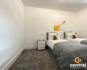 a bedroom with two beds and a night stand at 2 Bedroom Apartment by Central Serviced Apartments - Monthly Bookings Welcome - FREE Street Parking - WiFi - Smart TV - Ground Level - Family Neighbourhood - Sleeps 4 - 1 Double Bed - 2 Single Beds - Heating 24-7 - Trade Stays - Weekly & Monthly Offers in Dundee