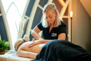 a woman sitting on a bed with a woman getting a massage at Sfeervol Boschalet 5 persoons met Sauna in Voorthuizen