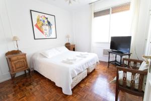a white bedroom with a bed and a television at Apartment in Recoleta in Buenos Aires