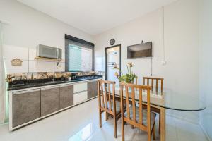 cocina con mesa de cristal y 2 sillas en Confortavel espaçoso Lof para familia en Joinville