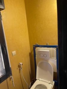 a bathroom with a toilet with a yellow wall at La maison du bonheur in Ouoran