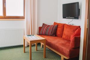 a living room with a red couch and a table at Pension Schindlau in Scharnstein