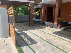een hek voor een huis met gras bij Joann Serviced Apartment in Thiruvalla