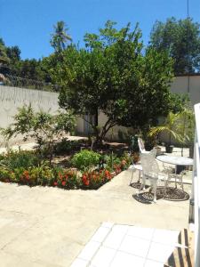 een patio met een tafel, stoelen en bloemen bij Casa da Ana in Camaçari