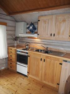 a kitchen with wooden cabinets and a sink and a stove at Rønlund Hyttepark in Ron