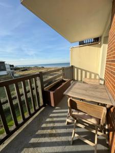 a wooden table and bench on a balcony with the ocean at Plage Cabourg 7bis in Cabourg