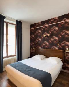 a bedroom with a large bed with a painting on the wall at Logis- Hôtel & Restaurant Le Montligeon in La Chapelle-Montligeon
