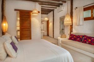 - une chambre avec un lit blanc et un canapé dans l'établissement Hotel Mawimbi, à Holbox