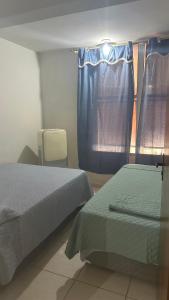 1 dormitorio con 2 camas y una ventana con cortinas en Residencial Maldonado Eckert - Enseada - Praia Grande, en São Francisco do Sul