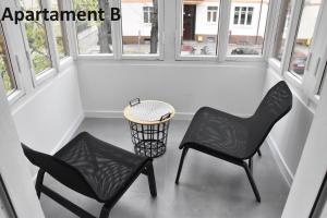 2 Stühle und ein Tisch in einem Zimmer mit Fenstern in der Unterkunft Apartament za 400m Plaża Sopot in Sopot
