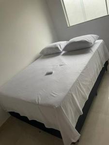 een bed met witte lakens en kussens in een kamer bij Casa Ampla em Guarajuba in Camassari