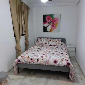- une chambre dotée d'un lit avec une couette imprimée de fleurs dans l'établissement El Patio de Lola, à Cordoue