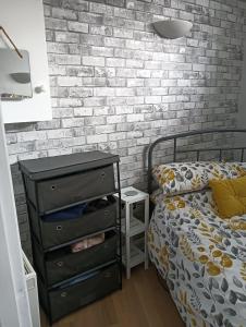 Schlafzimmer mit schwarzer Kommode und Ziegelwand in der Unterkunft Bijou Apartment in Berwick-Upon-Tweed