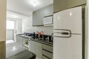 eine Küche mit weißen Schränken und einem weißen Kühlschrank in der Unterkunft Apartamento 2 dormitorios Novo Hamburgo Espaço Namibe in Novo Hamburgo