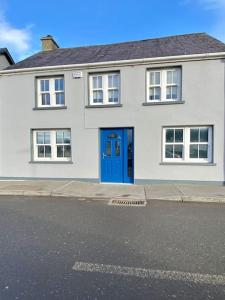 uma casa branca com uma porta azul numa rua em Modern family home em Castleisland