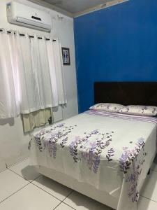 a bedroom with a bed with purple flowers on it at Casa de Everton e Tati in Triunfo