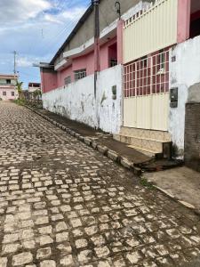 a cobblestone street in front of a pink building at Casa de Everton e Tati in Triunfo