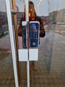 a person standing behind a glass with a cell phone holder at Coliving Synet in Mažeikiai