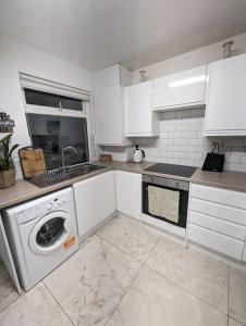 a kitchen with white cabinets and a washing machine at 3-bed Home For Football Fans in Liverpool