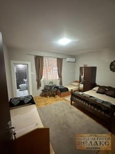 ein Schlafzimmer mit 2 Betten und ein Wohnzimmer mit einem Tisch in der Unterkunft Къща за гости Рупите , Guest House Relax Rupite in Rupite