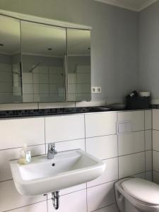 a white bathroom with a sink and a toilet at Ferienhaus in Dithmarschen in Barlt