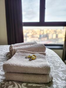 ein Stapel Handtücher auf einem Bett mit einem Fenster in der Unterkunft Belgrade Waterfront - Beograd na vodi Lux Apartman in Belgrad