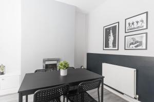 uma sala de jantar com uma mesa preta e cadeiras em Poppy's Project - July Road em Liverpool