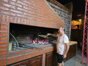 un hombre está cocinando comida en un horno de ladrillo en Hospedaje Los 7 Arcangeles en Termas de Río Hondo