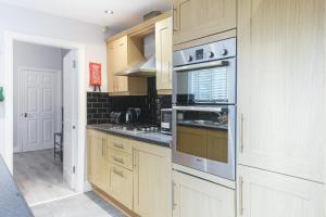una cocina con armarios de madera y electrodomésticos de acero inoxidable en Poppy's Project - July Road, en Liverpool