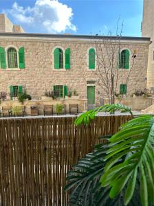 a brick building with green windows and a wooden fence at Jerusalem Center in Jerusalem